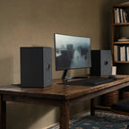 Onkyo GX-AiO 50 pair in black on a wooden desk, flanking a monitor
